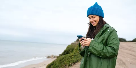 Woman with blue hat checking her cell phone